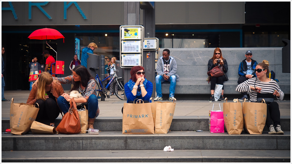 Passanten auf einer Treppe mit Papiertüten von Primark