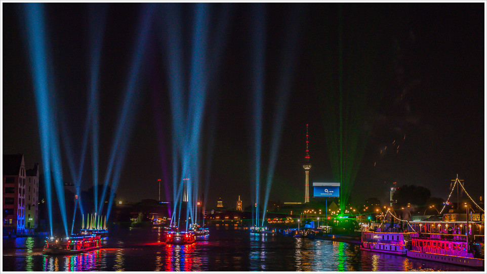 Nachtaufnahme von Schiffen mit Lichtstrahlen auf der Spree