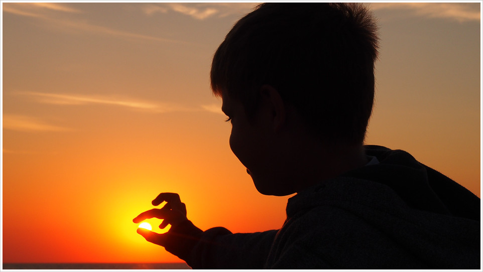 Kind im Schattenriss fängt die Abendsonne