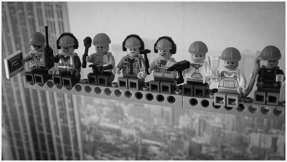 Legofiguren auf einem Träger, im Hintergrund die Kulisse von New York