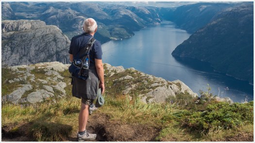 Mann schaut von oben auf Fjord