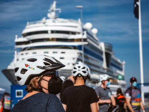 Frau mit Fahrradhelm vor AIDAsol im Hafen von Visby