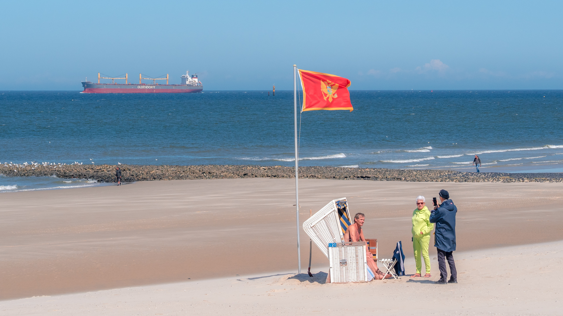 Strandkorb mit Fahne und Schiff im Hintergrund