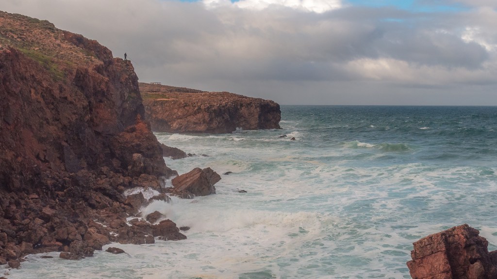Bild der Klippen am Atlantik bei Bordeira, hoch auf den Felsen steht ein Angler