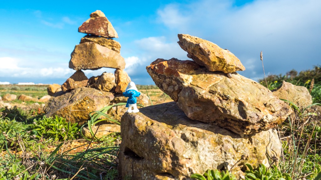 Eine Schlumpffigur auf kleinen Steintürmchen