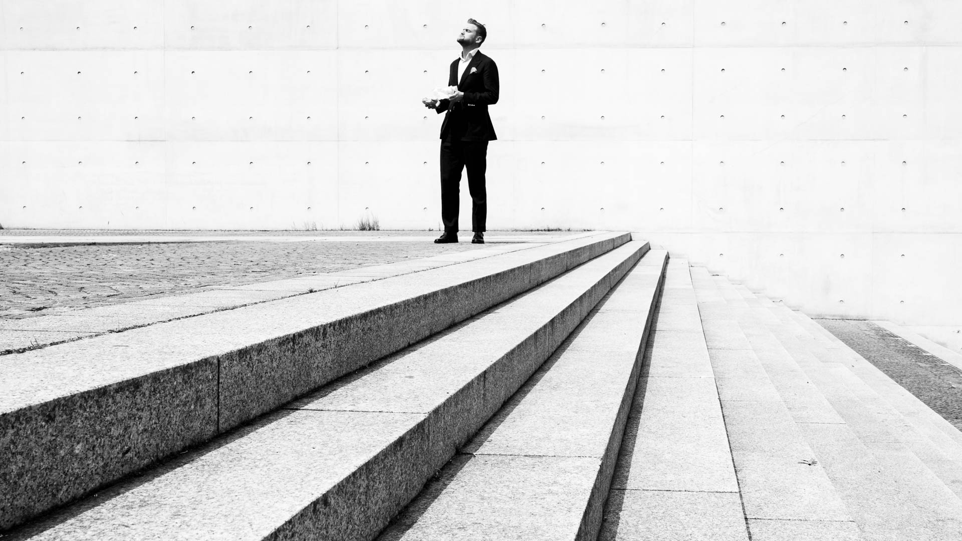 Ein Mann im Businessanzug steht seitlich oberhalb einer Treppe