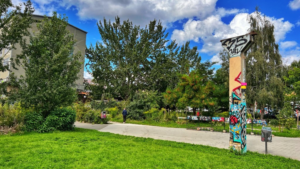 Wiese mit einem alten Betonpfosten, im Hintergrund eine Gebäude