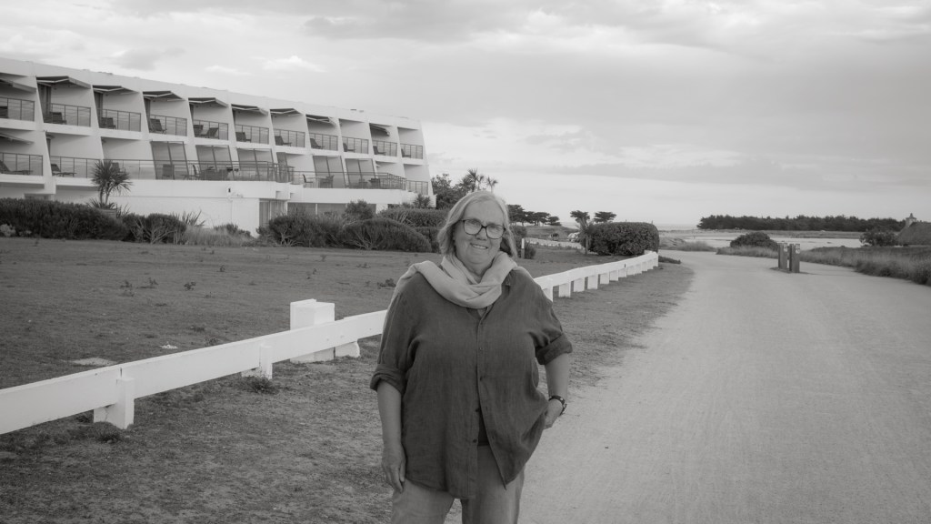 Eine Frau steht auf einem Weg vor einem Gebäude mit Balkons