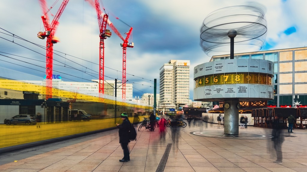 Weltzeituhr und verwischte Straßenbahn auf dem Alexanderplatz in Berlin