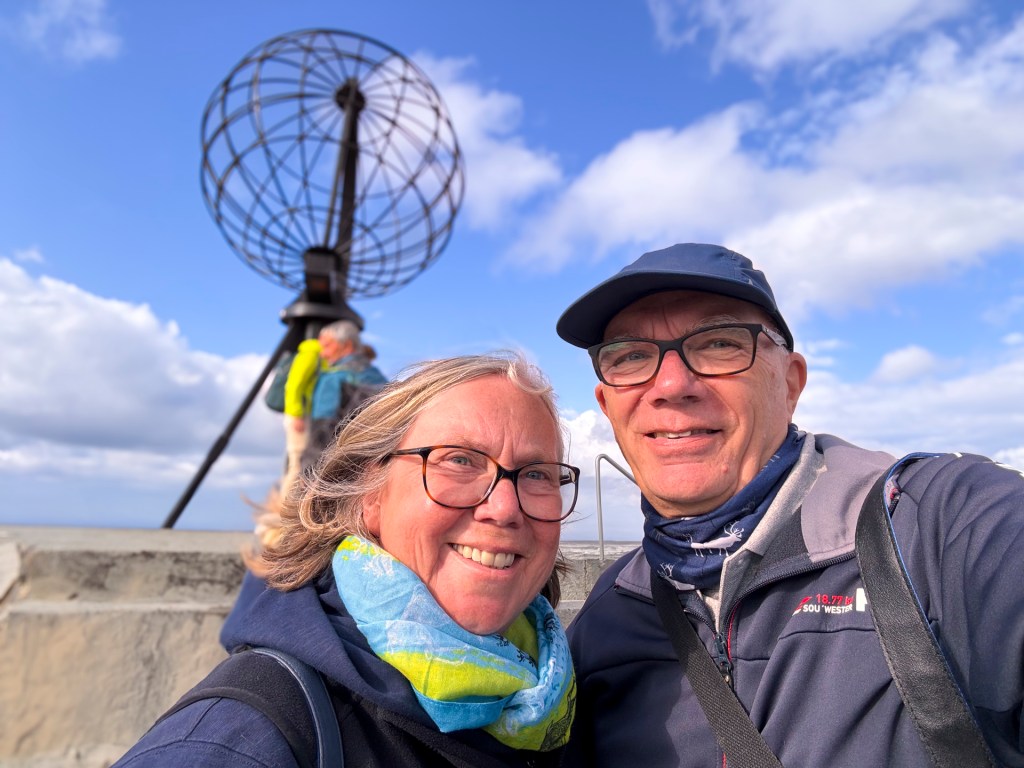 Eine Frau und ein Mann im Selfie vor der Nordkappkugel