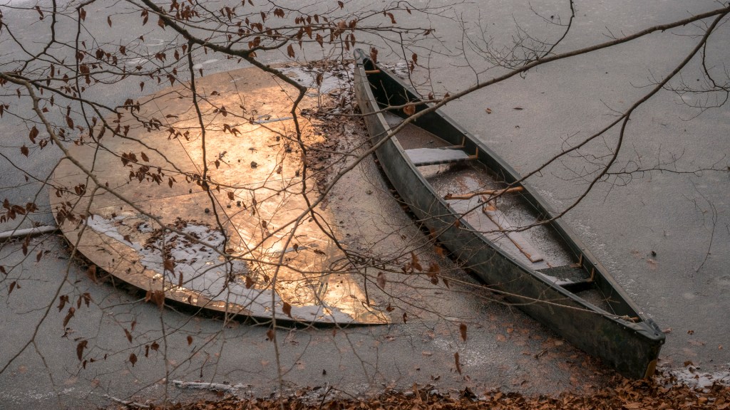 Eine Scheibe aus spiegelndem Metall mit einem Kanu in einem gefrorenen See