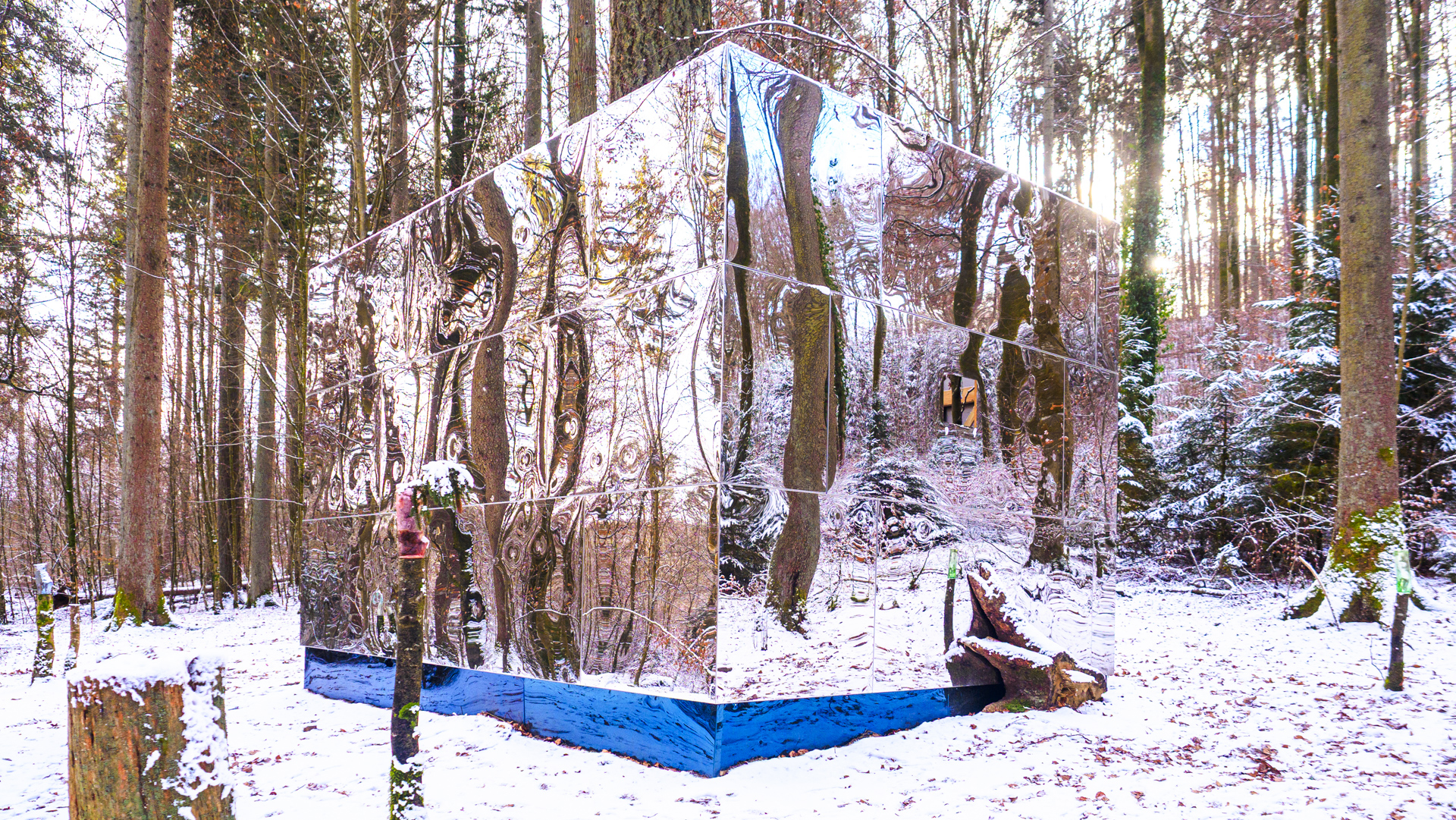 Ein Kubus mit spiegelnder Oberfläche in einem winterlichen Wald
