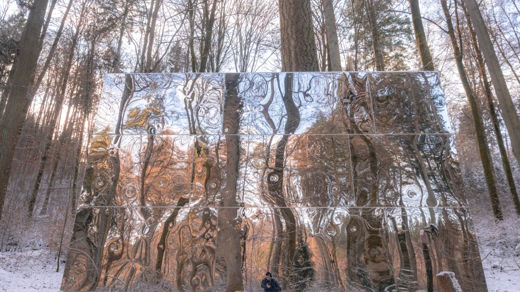 Ein Kubus mit spiegelnder Oberfläche in einem winterlichen Wald
