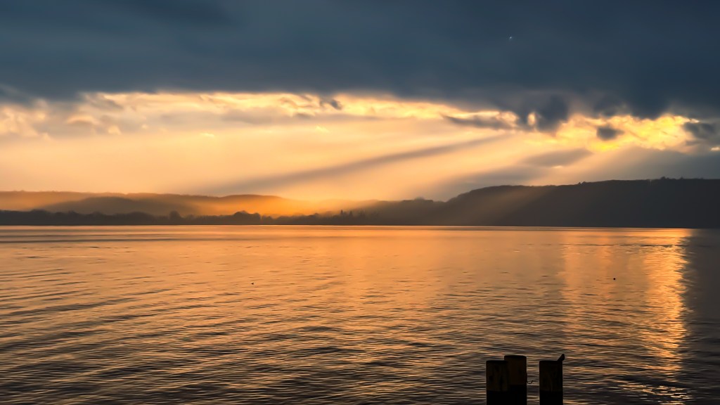 Die Sonne bricht aus den Wolken über Wallhausen und beleuchtet den Bodensee golden