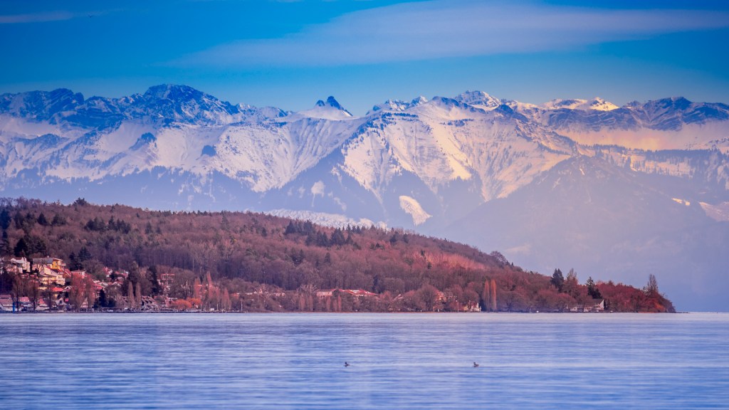 Blick über den Bodensee auf die Spitze von Unter-Uhldingen, im Hintergrund die Berge
