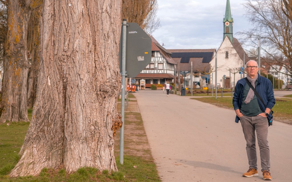 Eine Person steht auf einem Weg, im Hintergrund Gebäude